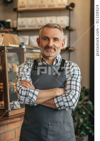 Man in apron with hands clasped looking at camera Man in apron with hands clasped looking at camera 91108924