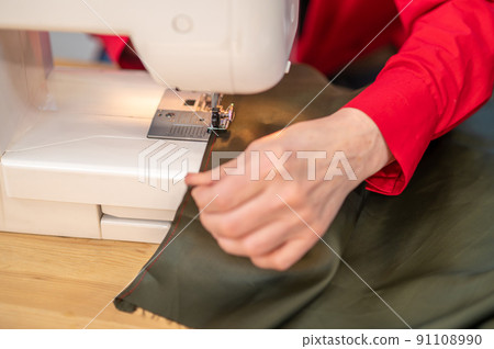 Top view of hands touching material sewing on machine Top view of hands touching material sewing on machine 91108990