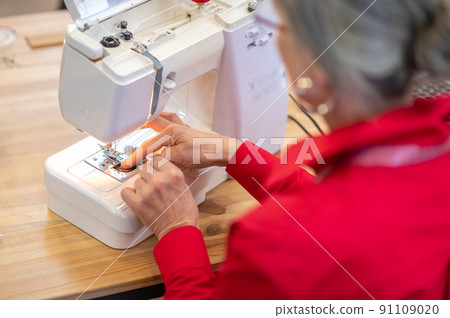 Back view of woman setting up sewing machine Back view of woman setting up sewing machine 91109020