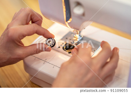 Top view of hands with sewing spool of thread 91109055