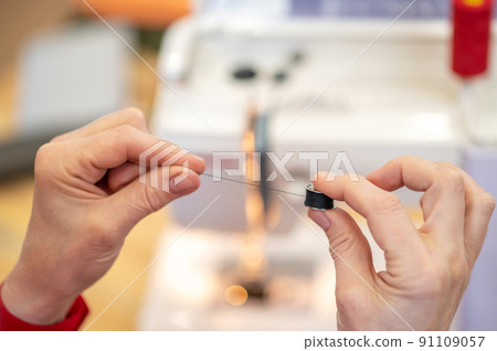 Hands holding sewing spool of thread Hands holding sewing spool of thread 91109057