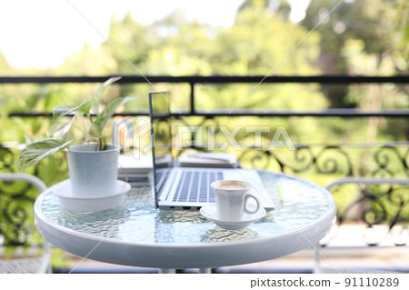 Laptop front view and coffee cup with notebooks on white glass table outdoor Laptop front view and coffee cup with notebooks on white glass table outdoor 91110289