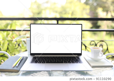 Laptop front view and coffee cup with notebooks on white glass table outdoor Laptop front view and coffee cup with notebooks on white glass table outdoor 91110290