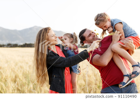 Happy family father of mother and two daughters sisters on nature at sunset.Carefree parents having fun with their kids on a field. Happy family father of mother and two daughters sisters on nature at sunset.Carefree parents having fun with their kids on a field. 91110490