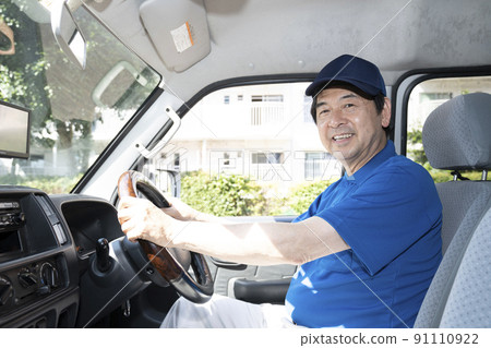 一個快遞員坐在駕駛座上,戴著帽子微笑 一個快遞員坐在駕駛座上,戴著帽子微笑 91110922