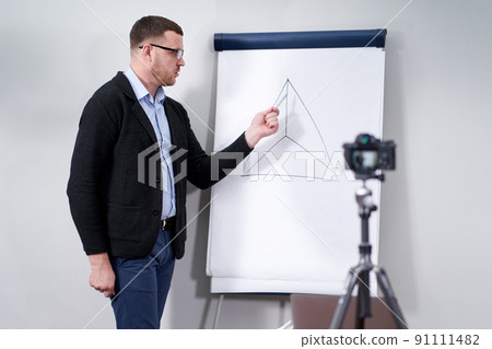 Young video blogger presenting important data on flipchart, online education concept Young video blogger presenting important data on flipchart, online education concept 91111482