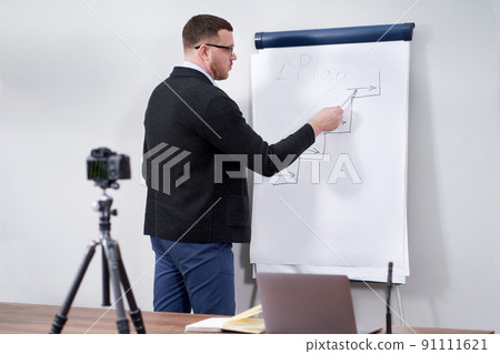 Young video blogger presenting important data on flipchart, online education concept Young video blogger presenting important data on flipchart, online education concept 91111621