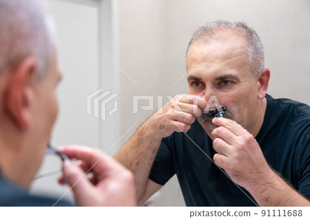 Man shaving with razor using foam in bathroom in the morning Man shaving with razor using foam in bathroom in the morning 91111688