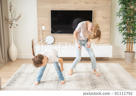 Two sisters having fun dancing in living room, happy family concept Two sisters having fun dancing in living room, happy family concept 91111792