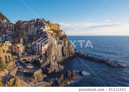 Rocky hills and colorful historic buildings of Manarola, Italy. 91112431