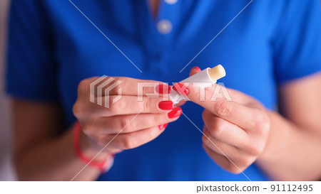 Woman with red manicure holding hygienic lipstick in hands closeup 91112495