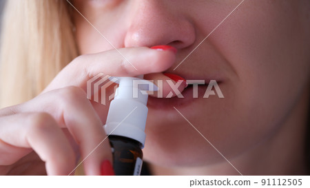 Woman instilling her nose with vasoconstrictor drops closeup 91112505