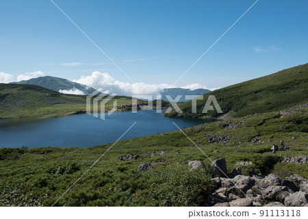 Hakuba Oike Sanso near Hakuba Oike to Mt. Shirouma, one of the 100 famous mountains in Japan in Toyama Prefecture, Nagano Prefecture, a snowy valley, clouds, a blue sky, and a view of climbers 91113118
