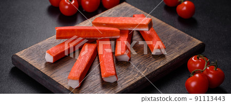 Crab sticks on a cutting Board with a knife. On black concrete background 91113443