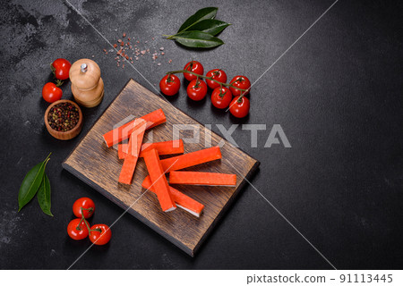 Crab sticks on a cutting Board with a knife. On black concrete background 91113445