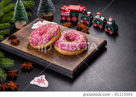 A beautiful doughnut with pink glaze and colored sprinkle on a christmas table 91113505