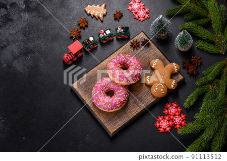 A beautiful doughnut with pink glaze and colored sprinkle on a christmas table A beautiful doughnut with pink glaze and colored sprinkle on a christmas table 91113512
