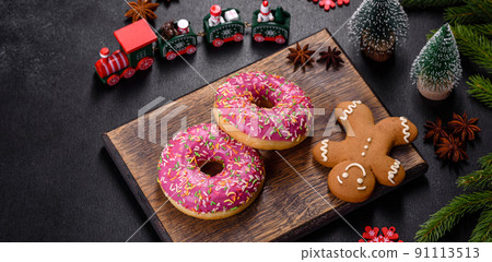 A beautiful doughnut with pink glaze and colored sprinkle on a christmas table A beautiful doughnut with pink glaze and colored sprinkle on a christmas table 91113513