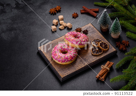 A beautiful doughnut with pink glaze and colored sprinkle on a christmas table A beautiful doughnut with pink glaze and colored sprinkle on a christmas table 91113522