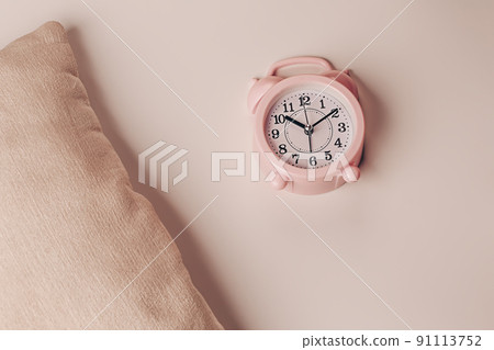 Pillow and alarm clock on a beige background. Healthy restful sleep concept. Pillow and alarm clock on a beige background. Healthy restful sleep concept. 91113752