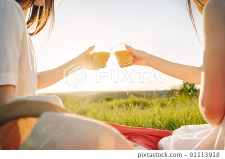 Two pretty sisters in a field of wheat. Beautiful two girls with long healthy hair enjoying nature on summer. Girls on a picnic. 91113918