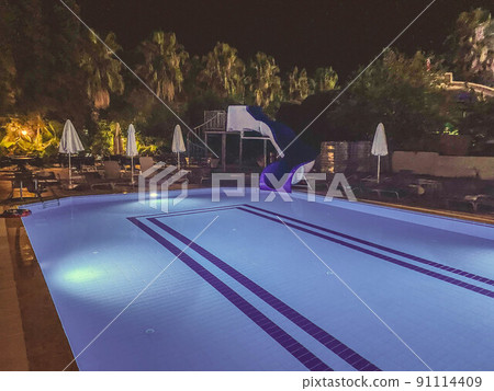 pool at the hotel in the evening, blue water in the pool. rest of tourists near the water in the evening. rest by the water, water park slides, trip by the water pool at the hotel in the evening, blue water in the pool. rest of tourists near the water in the evening. rest by the water, water park slides, trip by the water 91114409