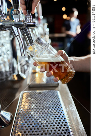 Pouring beer into a mug in a beer bar close-up. Beer bottling in the restaurant. The bar counter. Pouring beer into a mug in a beer bar close-up. Beer bottling in the restaurant. The bar counter. 91114885