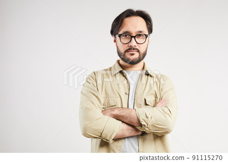 Portrait of serious handsome young Asian man in khaki shirt wearing stylish eyeglasses crossing arms against gray background Portrait of serious handsome young Asian man in khaki shirt wearing stylish eyeglasses crossing arms against gray background 91115270