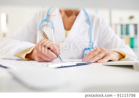 Close-up of unrecognizable doctor sitting at table and making notes in medical record while working with medical papers Close-up of unrecognizable doctor sitting at table and making notes in medical record while working with medical papers 91115786