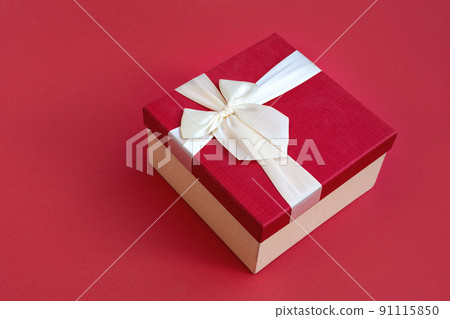 Top view of beautiful red gift box with satin light ribbon on red background. A gift for Christmas, New Year or a romantic Valentine's Day. Copy space for text. 91115850