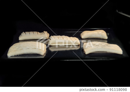 Five uncooked homemade buns with fruit jam in electric oven, black background Five uncooked homemade buns with fruit jam in electric oven, black background 91118098