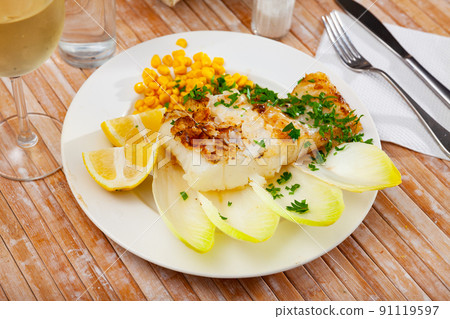 Delicious fried cod fillet with endive, corn, and greens Delicious fried cod fillet with endive, corn, and greens 91119597