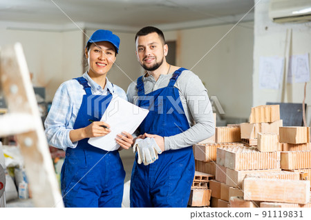 Smiling female foreman and bearded worker with papers at construction site Smiling female foreman and bearded worker with papers at construction site 91119831