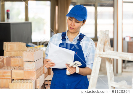 Female builder is studying the construction plan Female builder is studying the construction plan 91120264