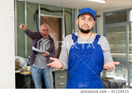 Perplexed builder in building under renovation with screaming customer Perplexed builder in building under renovation with screaming customer 91120415