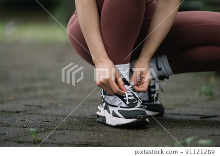一個為跑步運動鞋系鞋帶的女人 91121289