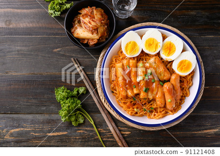 Korean spicy instant noodle with Tteokbokki, sausage and egg on wooden background, Table top view Korean spicy instant noodle with Tteokbokki, sausage and egg on wooden background, Table top view 91121408