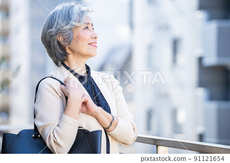 Middle woman standing with a bag in the business district Middle woman standing with a bag in the business district 91121654