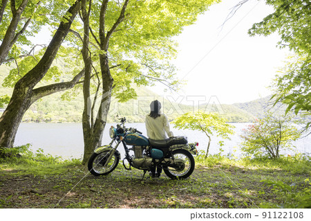 A young woman who comes by motorcycle to the lakeside and looks at the scenery. 91122108