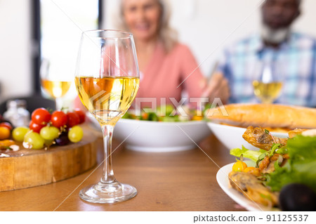 Close-up of wineglass with meal on dining table with seniors in background at nursing home 91125537