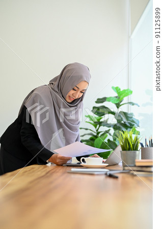 Professional muslim businesswoman or accountant wearing hijab, holding a financial report 91125899