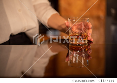 一個拿著玻璃杯的女人手上的酒吧 91127545