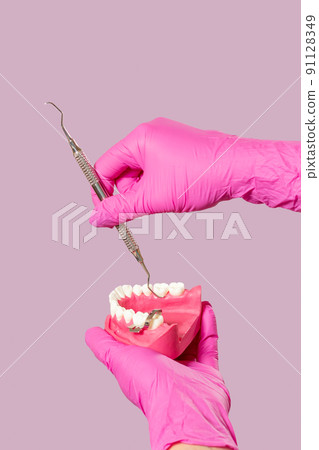 Dentist's hands with layout of the human jaw and dental restoration instrument. 91128349