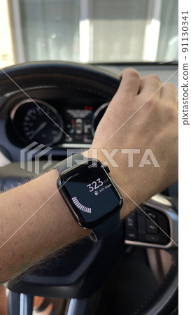 The clock on the hand of a man in the car shows the consumption of gasoline The clock on the hand of a man in the car shows the consumption of gasoline 91130341