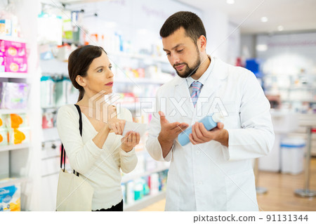 Female buyer consults the pharmacist which lotion or ointment to buy at pharmacy Female buyer consults the pharmacist which lotion or ointment to buy at pharmacy 91131344