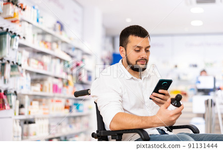 Disabled man photographing medicine product in drugstore Disabled man photographing medicine product in drugstore 91131444