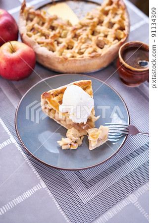 Piece of Fresh homemade Traditional Apple Pie with ice cream on a domestic kitchen Piece of Fresh homemade Traditional Apple Pie with ice cream on a domestic kitchen 91134309