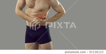 Young man suffering from pain in his left side standing on copy space background Young man suffering from pain in his left side standing on copy space background 91136123