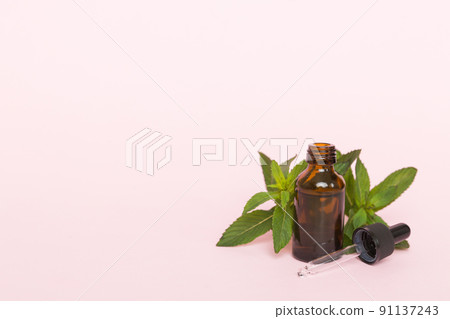 Natural Mint Essential Oil in a Glass Bottle. organic cosmetics with herbal extracts of mint on colored background 91137243