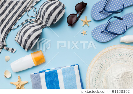Woman swimwear and beach accessories flat lay top view on colored background Summer travel concept. bikini swimsuit, straw hat and seasheels. Copy space Top view Woman swimwear and beach accessories flat lay top view on colored background Summer travel concept. bikini swimsuit, straw hat and seasheels. Copy space Top view 91138302
